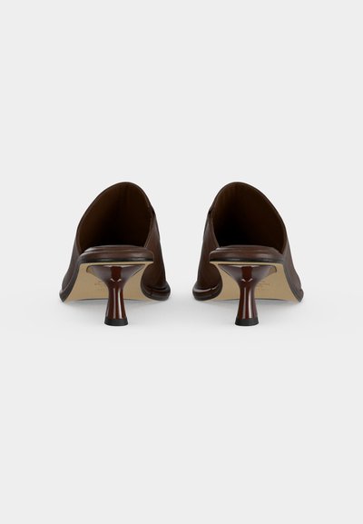 Pair of dark brown leather mule heels with flared, curved kitten heels shown from the back on a white background.