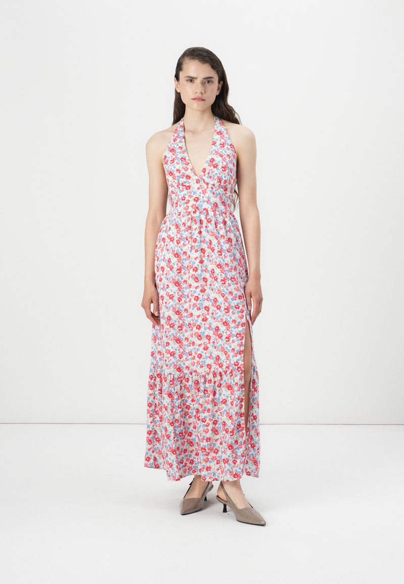 Rochie maxi florală cu guler halter, având un decolteu adânc în V, fante laterale și un tiv volanat în nuanțe de roșu, roz și albastru pe un fundal alb.