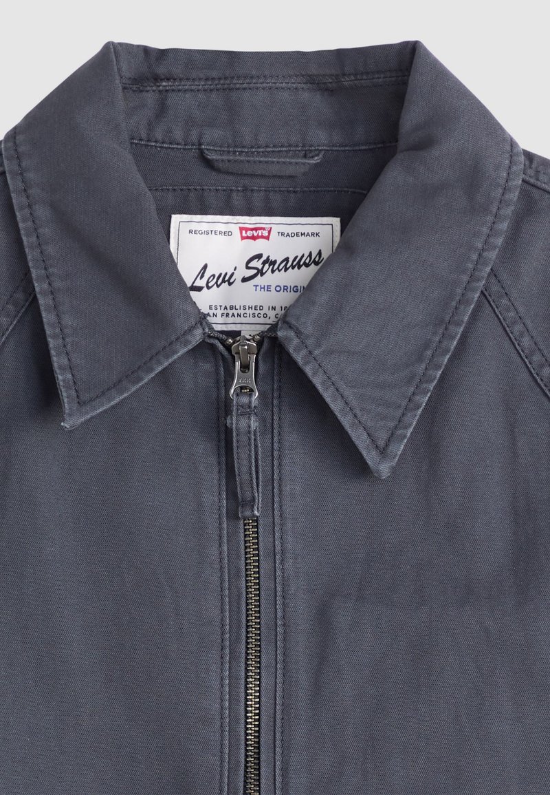 Graue Jeansjacke mit Kragen, Frontreißverschluss und Levi Strauss-Label. Hat eine glatte Textur und ein strukturiertes Design.
