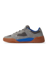 Grijze suède en mesh sneaker met blauwe accenten en een bruine rubberen zool. Het heeft een laag profiel en een vetersluiting. Gevoerde bovenkant voor grip.