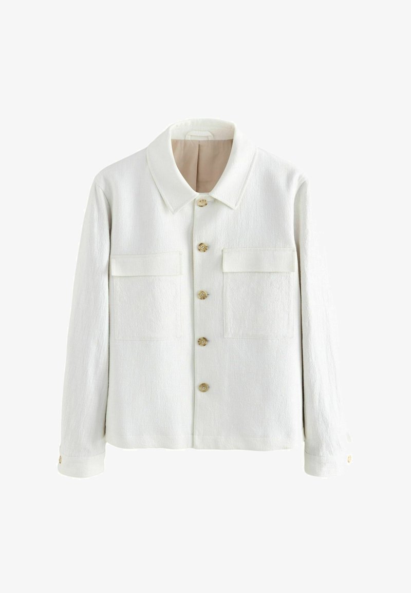 Valge jakk, mis on valmistatud tekstuurilisest kangast, omades teravat kraed, nööpidega esist lukku ning kahte rinna taskut klapiga. Nööbid on heledast puidust.