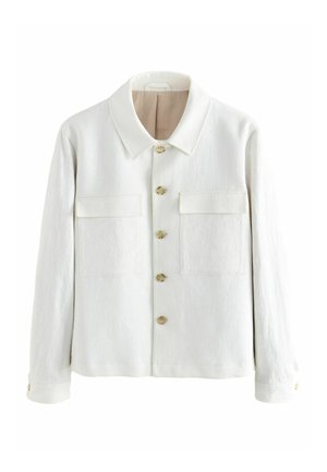 Veste blanche en tissu texturé, dotée d'un col pointu, d'une fermeture à bouton sur le devant et de deux poches poitrine avec rabat. Les boutons sont en bois clair.