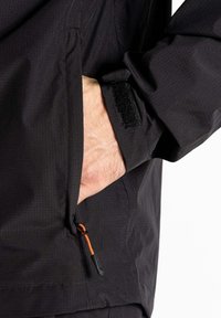 Sort vandtæt jakke med struktureret stof, der har en yderlomme med en orange lynlås, justerbare ærmer med velcro-lukning.