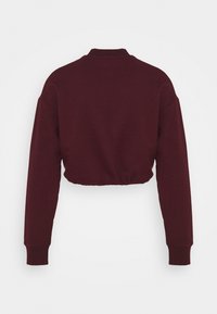 Sweat-shirt court rouge foncé à manches longues avec poignets et col côtelés, vu de dos sur un fond clair uni.