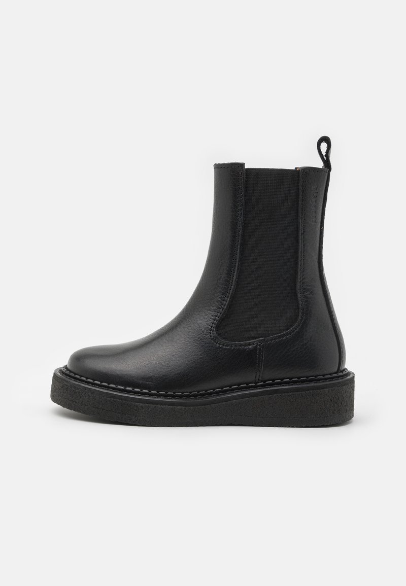 Černá kožená kotníková bota s elastickými bočními panely a texturovanou podrážkou. Má poutko na zadní straně a prošívání podél podrážky.