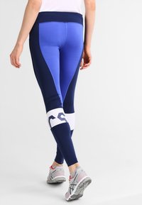 Granatowe legginsy sportowe z wysokim stanem, z kolorowymi panelami i białym logo na łydce.