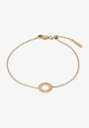 Guldtonat metallarmband med en länkad hjärtformad mittdel, tunn kedjedesign, justerbar låsning och en liten taggdetalj.