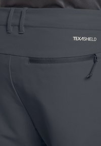 Graue Hose aus einem glatten, leichten Stoff. Enthält eine Reißverschlusstasche und elastische Details am Bund mit dem Logo "TEXASHIELD".