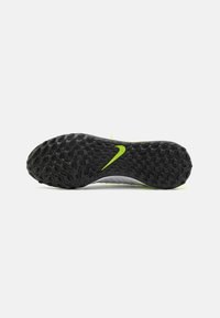 Suela de crampones Nike de fútbol con una superficie de goma negra texturizada, con patrones en relieve y un acento de logo verde brillante.