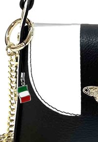 Sac à main en cuir noir et blanc avec une bandoulière en chaîne dorée, des éléments en or et un porte-clés avec un petit drapeau italien.