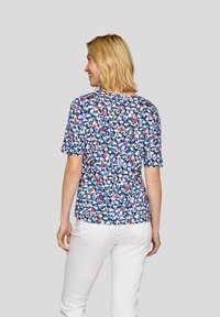 Kurzärmliges Oberteil mit navyfarbenem Grund, das ein verstreutes Blumenmuster in Rot, Weiß und Blau zeigt. Leichter Stoff, lässige Passform.