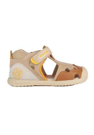 Sandalo per bambini beige e marrone con punta aperta, cinturino in velcro, pelle traforata e suola in gomma progettato per comfort e supporto.