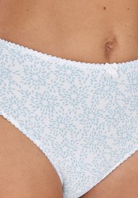 Weißer Baumwoll-Slip mit einem hellblauen Blumenmuster. Verfügt über gewellte Kanten und ein kleines Schleifendetail am Bund.