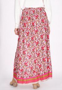 Langer Blumenrock in Pink und Weiß, mit einem lebhaften Blumenmuster in Rot und Grün, elastischem Taillenbund und einem dekorativen gestreiften Saum.