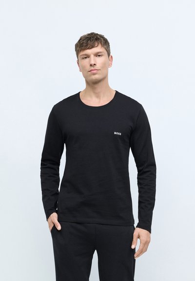 Chemise noire à manches longues avec un col rond et un branding subtil "BOSS" sur la poitrine, associée à un pantalon noir. Texture lisse.