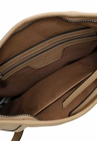Tan leather handbag interior with a brown fabric lining. Features a zip pocket, flat compartment, and stitched detailing on leather accents.