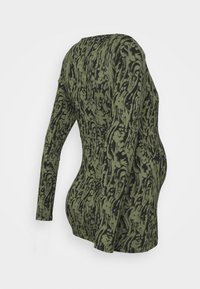 Långärmad gravidtröja i olivgröna med ett flytande, abstrakt svart mönster. Mjukt tyg, figurnära silhuett och rundad nederkant.