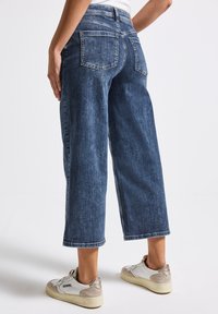 Bredbyxor i mörkblå denim med en blekt finish, med medelhög midja, två bakfickor och något fransade nederkanter.