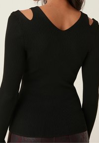 Czarny, prążkowany top z długim rękawem, z wycięciami na ramionach i dekoltem w kształcie litery V, wykonany z teksturowanej tkaniny o dopasowanym kroju.