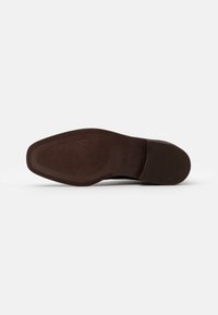 Sole di scarpa in pelle marrone scuro con motivo di grip testurizzato, forma leggermente rettangolare e caratteristiche di design classico. Finitura liscia nel complesso.