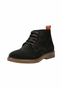 Stivale alla caviglia in suede nero con punta tonda, chiusura con lacci e un accento in pelle marrone a contrasto sul tacco. Suola in gomma testurizzata.