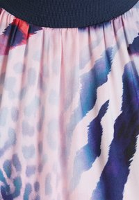 Kukalliskuvioinen hame, jossa joustava laivastonsininen vyötärönauha. Pehmeä kangas, jossa vaaleanpunaisia, purppuran ja sinisen sävyisiä liukuvärejä, jotka muistuttavat eläinkuoseja.