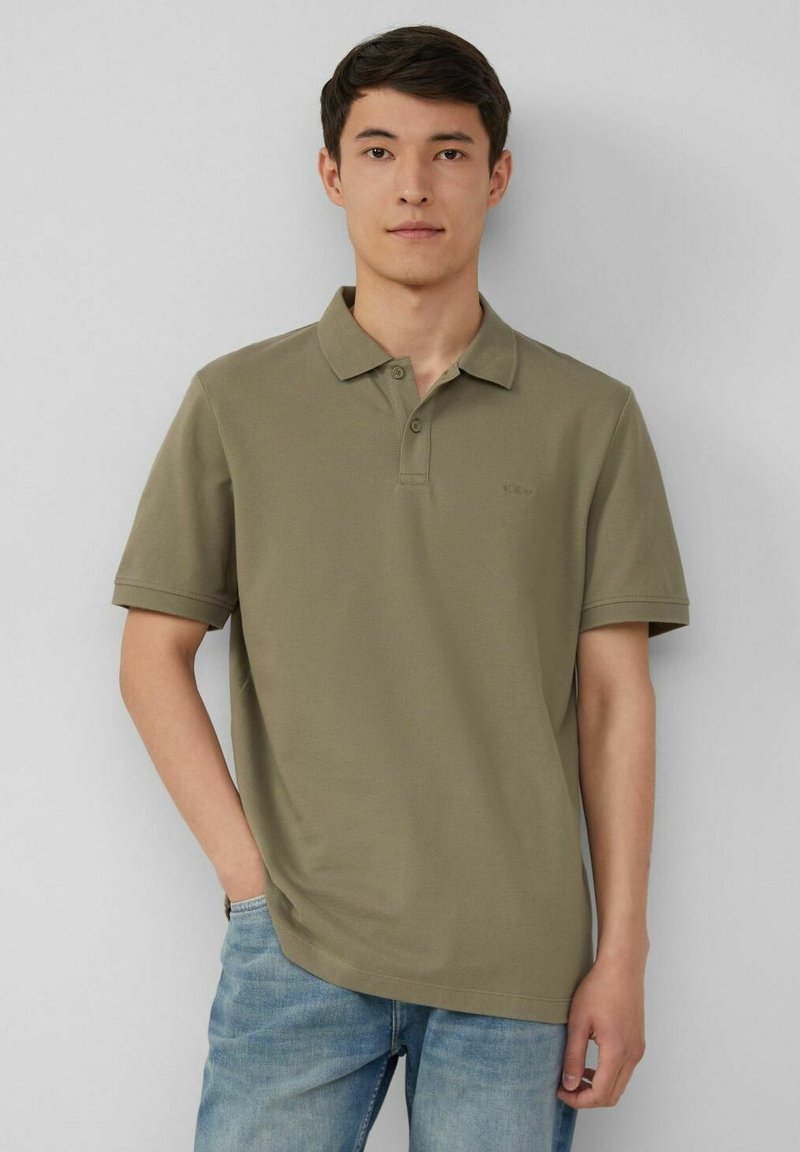 Olivgrünes Poloshirt mit klassischem Kragen, kurzen Ärmeln und drei Knöpfen. Weicher Baumwollstoff mit dezentem Logo auf der Brust.