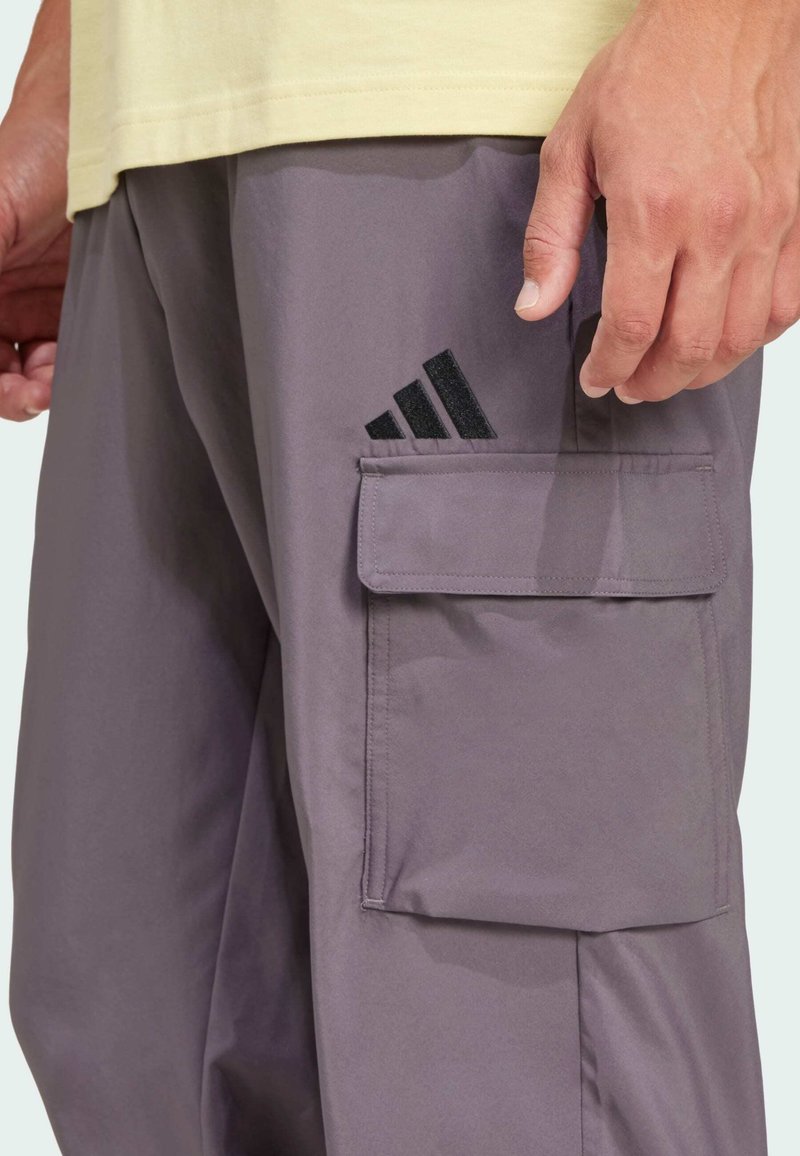 Pantalones cargo grises con un bolsillo lateral, con un logotipo de Adidas negro. Confeccionados en tejido ligero, de textura suave y de corte relajado.