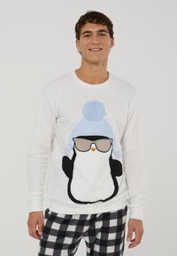 Felpa bianca con design di un pinguino che indossa un cappello a pompon blu e occhiali da sole. Tessuto morbido, maniche lunghe, vestibilità comoda. Pantaloni a scacchi neri.