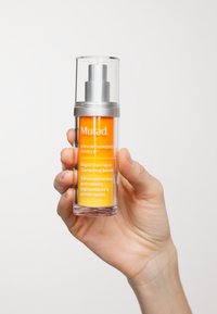 Murad Rapid Dark Spot Correcting Serum i en klar glasflaska med ett silverlock. Ljusorange vätska, märkt med vit text.