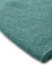 Coperta in lana blu verde lavorata a maglia con una superficie morbida e testurizzata e un bordo ripiegato. Il tessuto ha un motivo sottile e un'eccellente caduta.