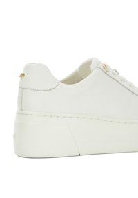 White leather sneaker with a thick white sole, featuring subtle stitching, a rounded heel, and a small gold logo accent near the back.