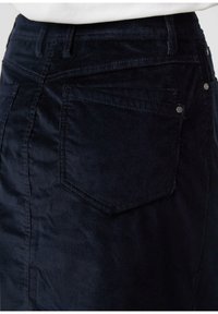 Marine corduroy rok met een getailleerde taille, twee achterzakken, subtiele ribbelstructuur en accenten in zilverkleurige hardware.