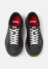 Black suede and leather sneakers with white laces, red insoles, and a gum sole; streamlined design enhances flexibility and comfort.