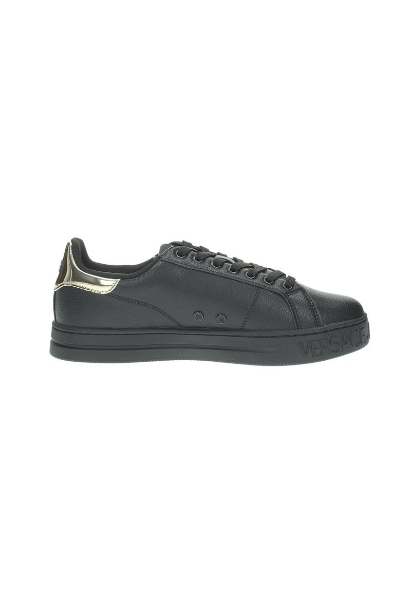 Baskets en cuir noir avec une surface texturée, présentant un accent doré au niveau du talon, des lacets noirs et une semelle plate noire. Marque Versace visible.