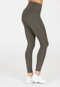 Olijf groene high-waisted leggings met ribbelaccenten op de onderbenen. Gemaakt van rekbaar materiaal, met platte naden en een gladde textuur.