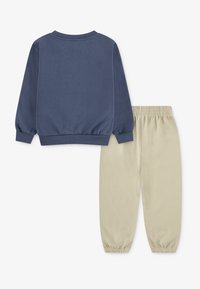 Sweatshirt and pants set, navy blue cotton sweatshirt with ribbed cuffs, paired with beige cotton pants featuring an elastic waistband.