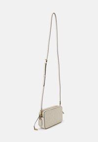 Beżowa torba na ramię wykonana z teksturowanej skóry, z zamkiem błyskawicznym, regulowanym paskiem i złotymi elementami metalowymi. Widoczny wytłoczony wzór logo.