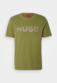 Olchowa bawełniana koszulka z krótkim rękawem z napisem "HUGO" w wzór w jodełkę, z okrągłym dekoltem.