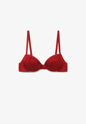 Červená podprsenka s kosticí a nařasením, s tenkými nastavitelnými ramínky a hladkými bočními pásky na bílém pozadí.