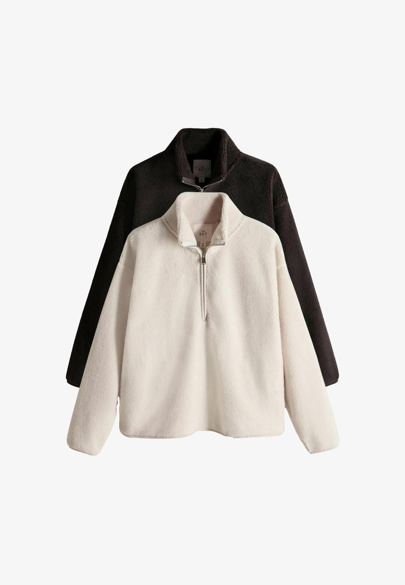 Zestaw polarowych pulowerów z suwakiem do ćwiartki. Jeden w kolorze białym, drugi czarny. Miękka faktura, luźny krój i stójka.