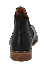 Botas de cuero negras hasta el tobillo con un tacón apilado marrón, paneles laterales elásticos y un detalle del logo en la parte trasera. Acabado liso y diseño ajustado.