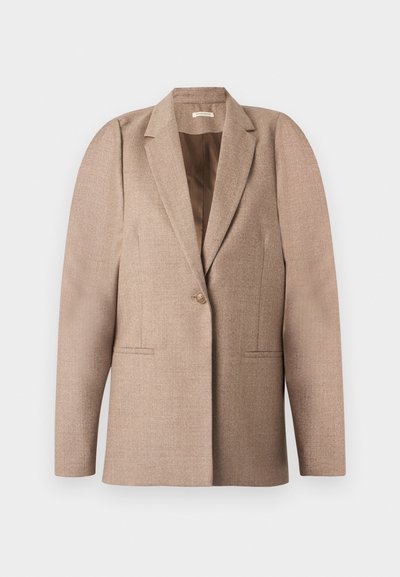 Blazer beige en tissu texturé, avec une fermeture à un bouton, un col à revers et deux poches avant. Design structuré aux épaules.