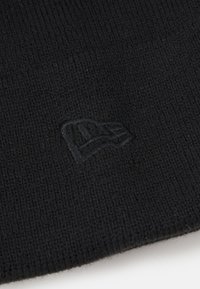 Gorro de punto negro con textura acanalada. Presenta un sutil logotipo bordado en hilo oscuro. Material suave y elástico para mayor comodidad.