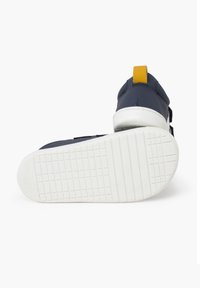 Tumesinine spordijalats, millel on tekstureeritud kummist tald, valge vahetald ja kollane kandtab. Omab reguleeritavaid rihmasid sulgemiseks.