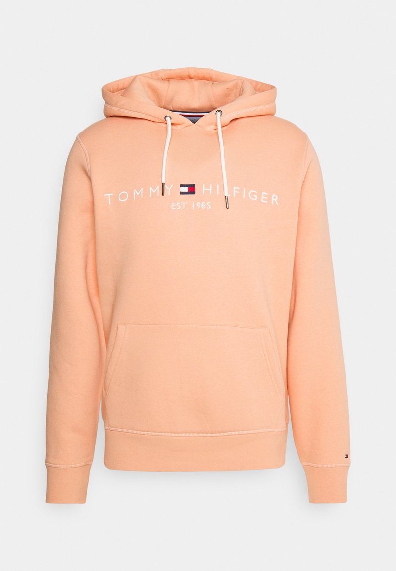 Sudadera con capucha color durazno hecha de algodón, con un bolsillo frontal, texto del logo en blanco y cordones con puntas de metal.