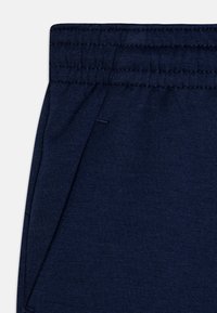 Des pantalons en mélange de coton bleu marine dotés d'une taille élastique côtelée, de poches latérales et d'une texture lisse avec un design simple.