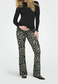 Svart långärmad topp med volangkanter, i kombination med högmidjade, utsvängda byxor med ett zebramönster i svart och beige.