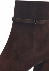 Bruine suède enkellaars met een ronde neus, een subtiele banddetail en een slank silhouet met een lage hak.