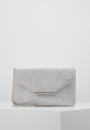 Sølvglitrende clutch-taske med konvolutklap og metalskinne-detalje, hvilende på en hvid overflade med en kæderem på siden.